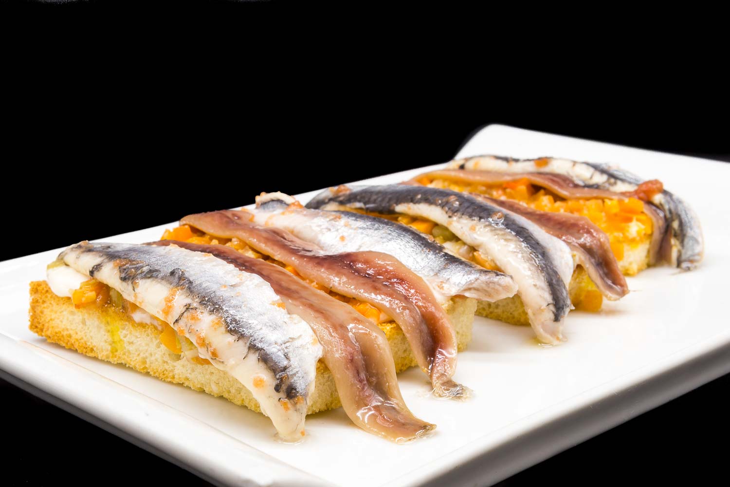 Toasts of anchovies and sardines on vegetables