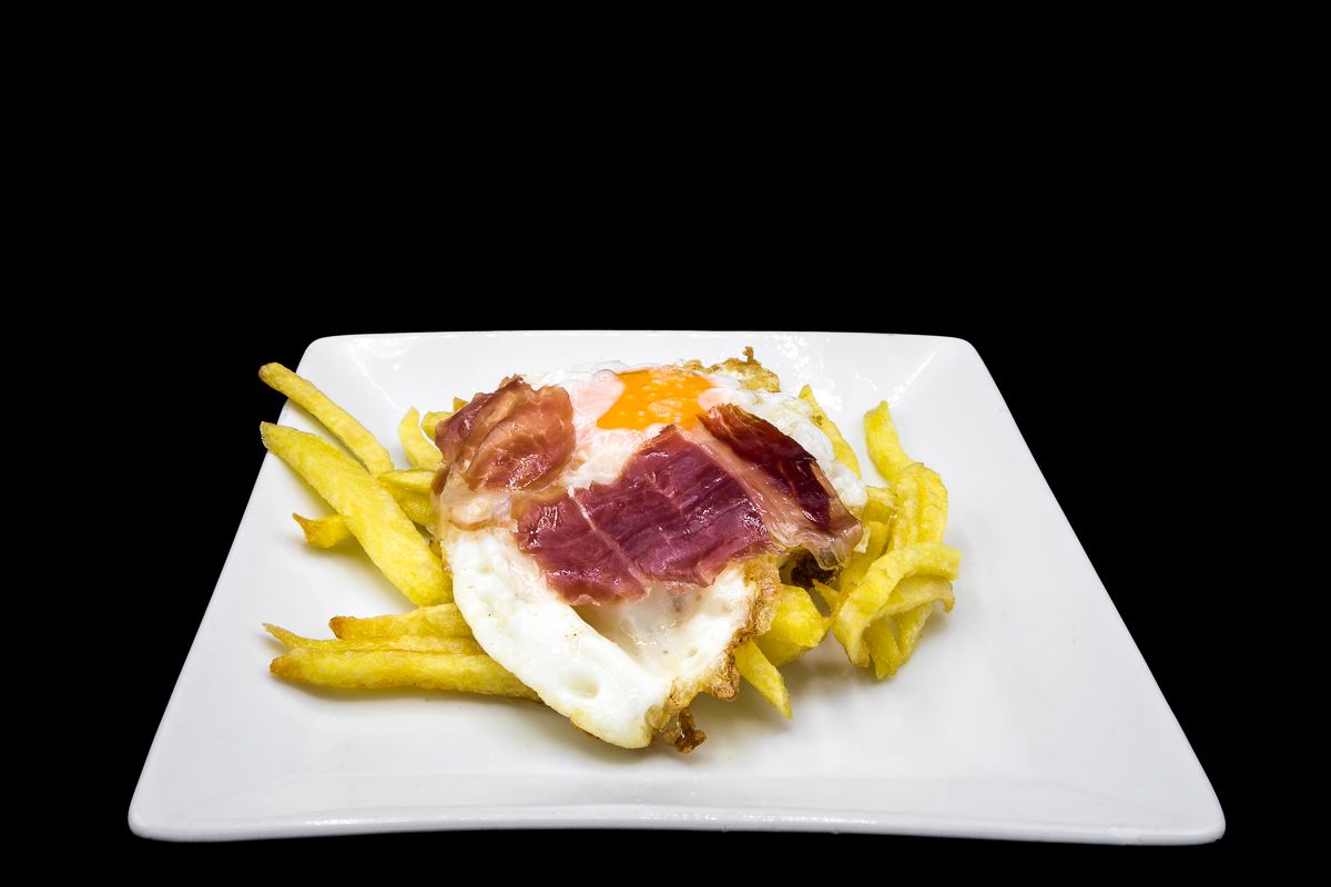 Fried egg with french fries and Serrano ham