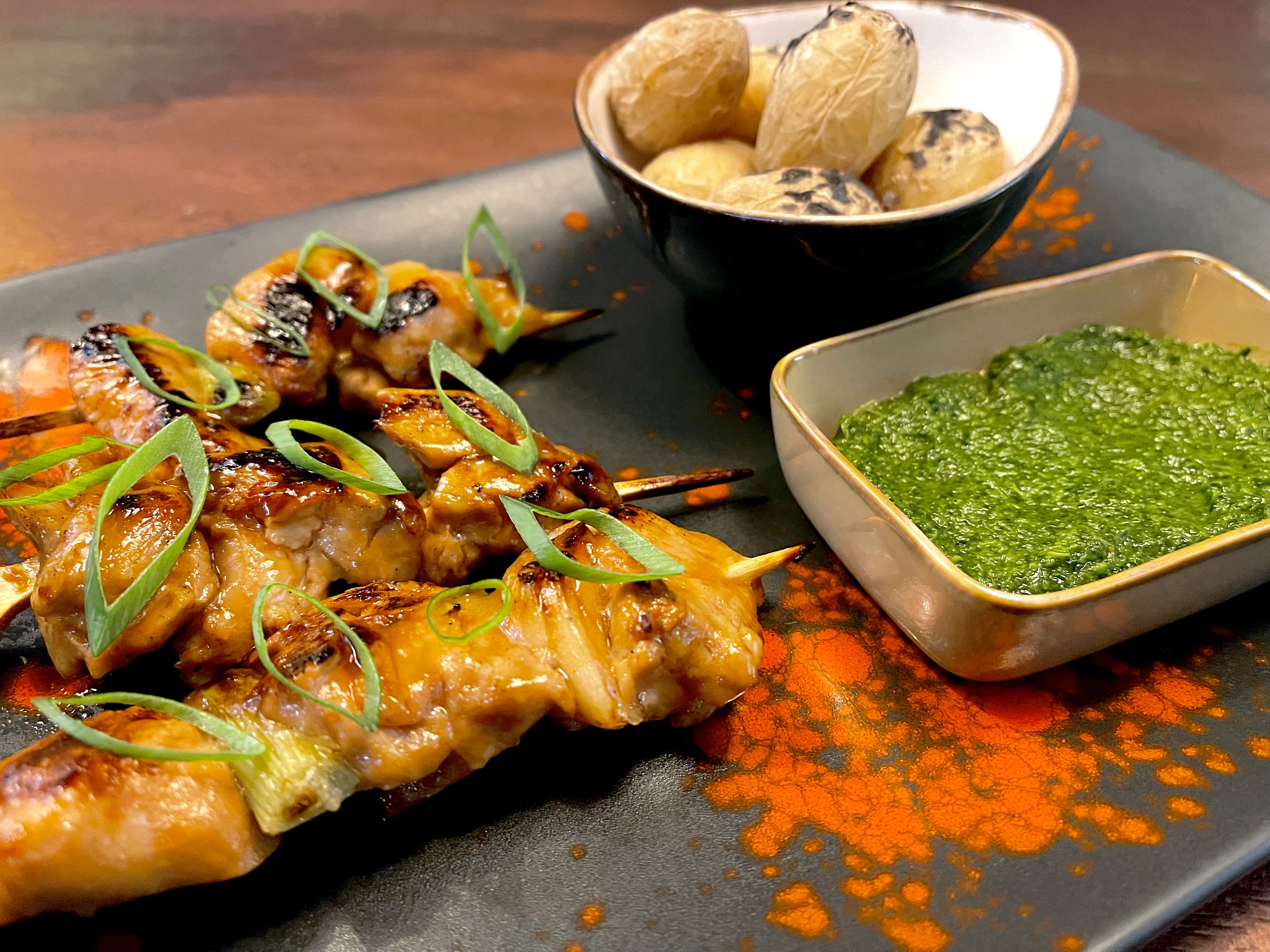 Yakitori chicken skewer with spring onion and wrinkled baby potatoes and green mojo sauce