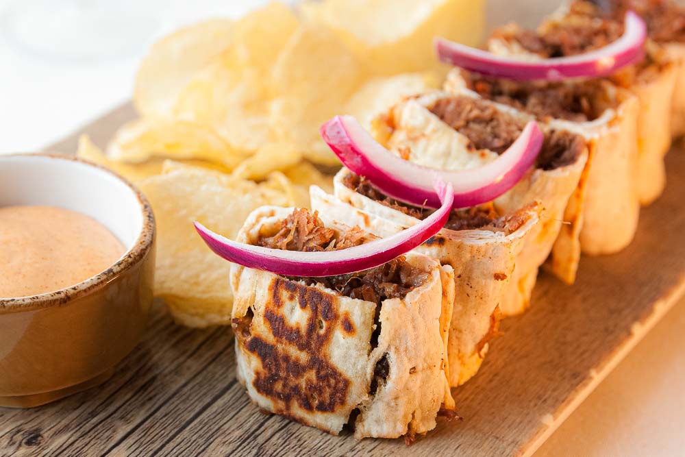 Grilled bull tail burrito with spicy sauce and pickled onion