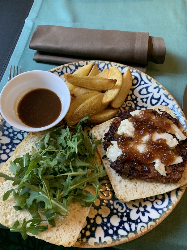 Vegan burger with vegan cheese, caramelized onion and arugula in focaccia bread.