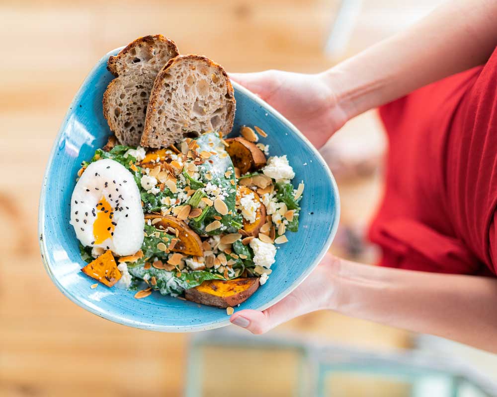 NOMADE SALAD: Arugula and spinach mix with roasted sweet potato, feta cheese, sliced almonds, a poached egg and yogurt sauce