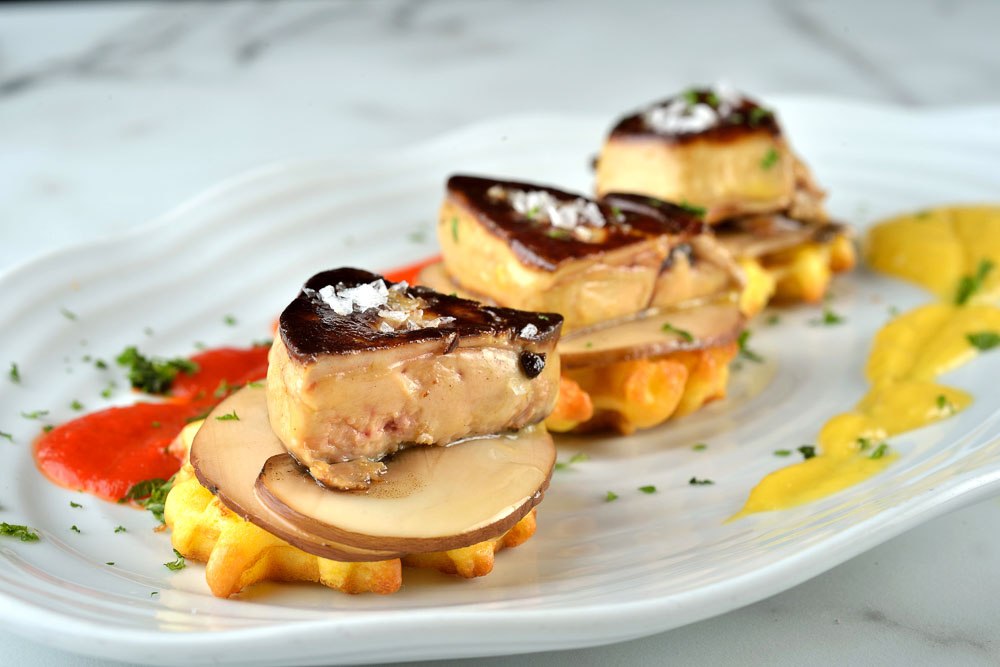 Foie gras grelhado sobre pequenos waffles e carpaccio portobello com geléia
