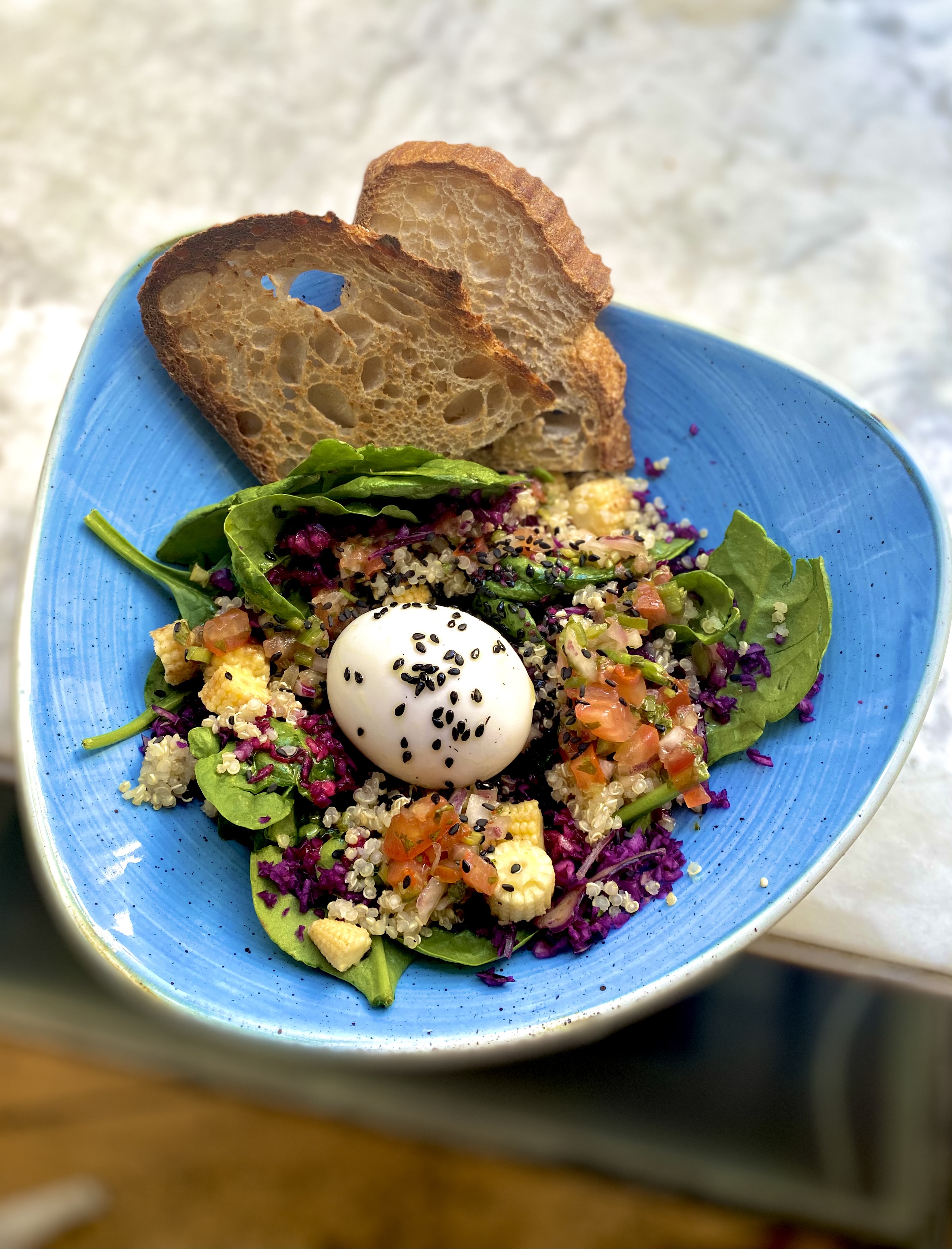 RAINBOW SALAD : Mix of spinach and quinoa with red cabbage, sweet corn, feta cheese, pico de gallo and an egg. Served with sourdough bread. 