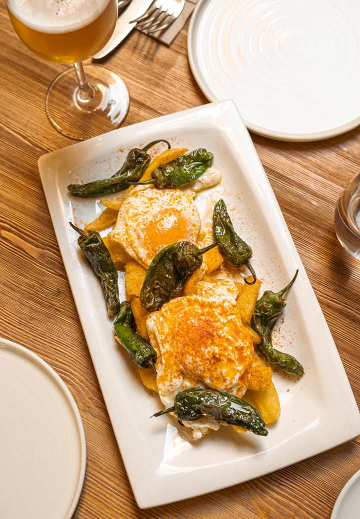 Pair of fried eggs with potatoes and Padrón peppers