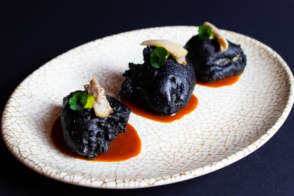 Rocas negras de merluza sobre crema de pimiento rojo japo, emulsión de albahaca y papada