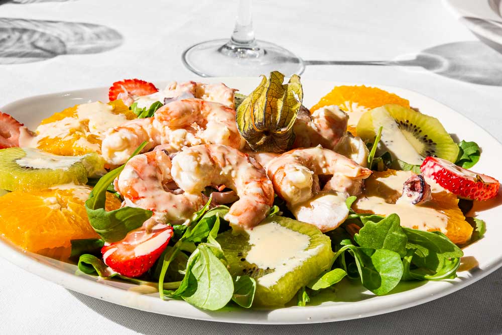 Garnelen-Kraken-Salat, frisches Obst, Rucola, Tomaten, Honig und Senf-Vinaigrette